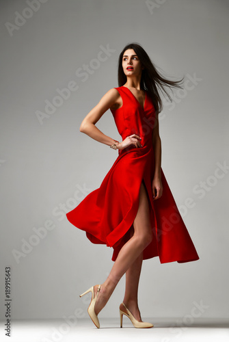 Obraz na płótnie Pretty brunette woman in formal red dress stiletto heels shoes w salonie