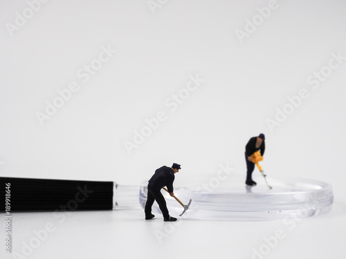 Miniature construction worker is working on a magnifying glass on a white background.