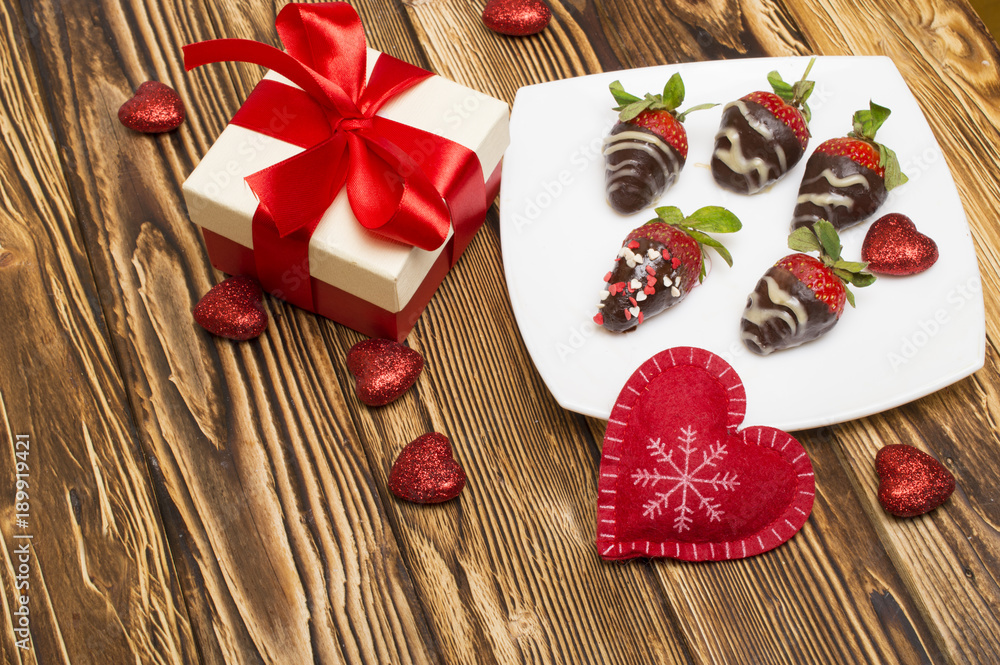 Fresh strawberries dipped in dark chocolate, gift and heart on wooden background. Valentine's Day.