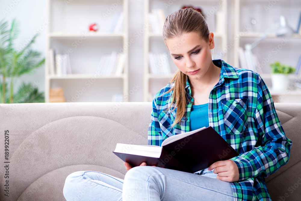 Female student reading the book sitting on the sofa Female student reading the book sitting on the sofa