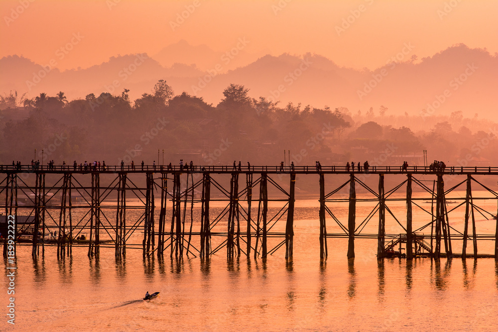 Obraz premium Silhouette old wooden bridge with mountain background and sunlight