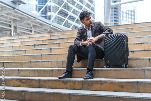 Business man sitting on stair with luggage in the routine of working with determination and confidence. concept of business trip travel and transportation.