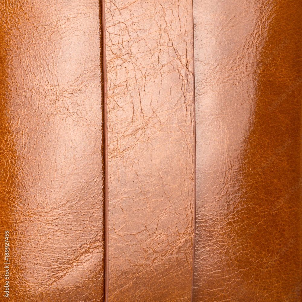 Fototapeta premium Luxurious light brown shiny leather with highlights, gradients and seams closeup