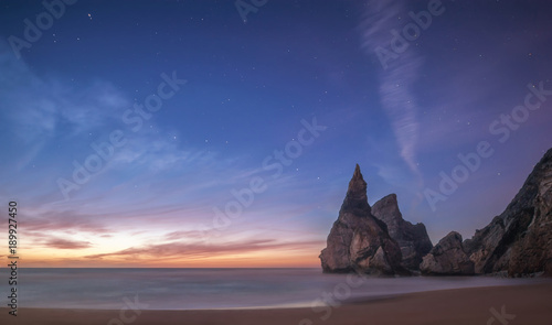 beautiful Atlantic ocean view horizon with sandy beach, rocks and waves at sunset. Sintra, Portugal
