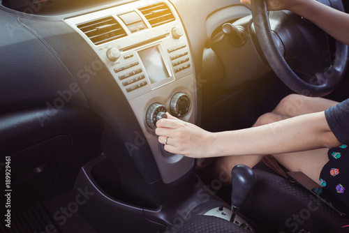 Hand of female turning on car air conditioning system,Button on dashboard inside car panel