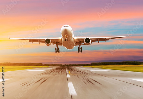 Passenger airplane landing at sunset on a runway.