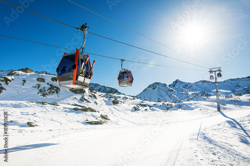 ski lift gondolas against blue sky over slope at ski resort on sunny winter day at Italy Alps