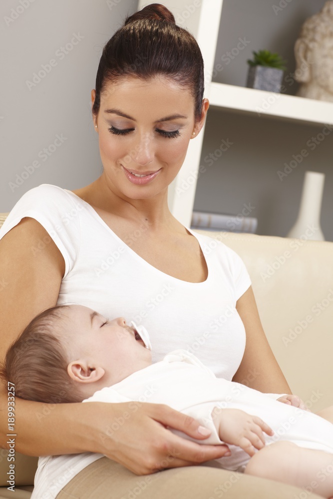 Young mother holding sleeping baby tenderly Young mother holding sleeping baby tenderly