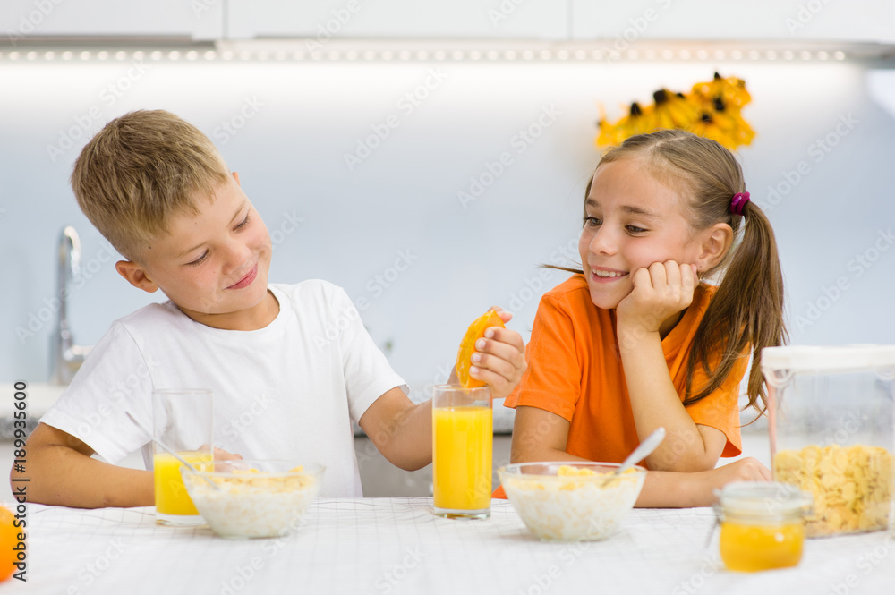 Little boy squeezes orange juice for breakfast his sister Little boy squeezes orange juice for breakfast his sister