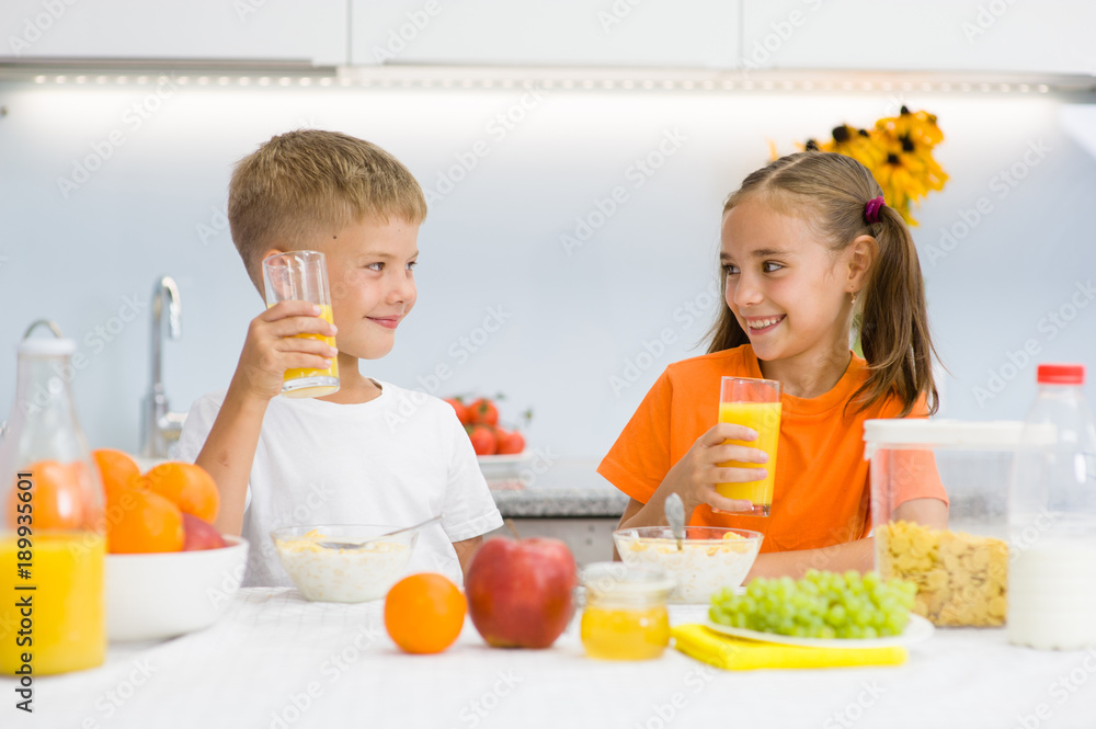 Happy children drink orange juice for breakfast Happy children drink orange juice for breakfast