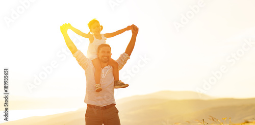 father's day. child daughter sits on her dad shoulders outdoors on a summer .
