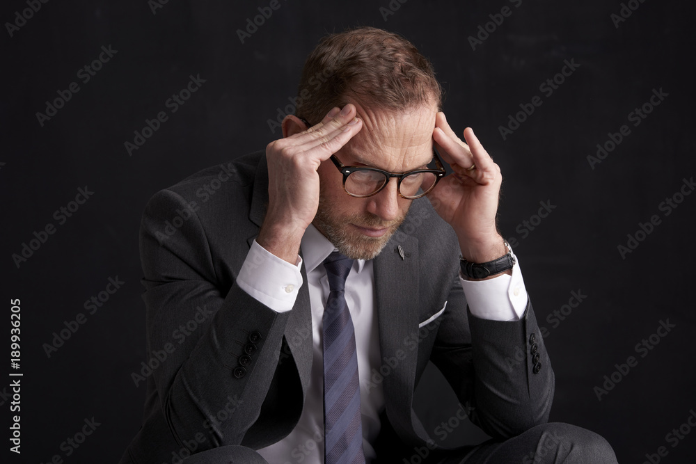 Stressful businessman portrait. Studio shot against dark background. Businessman wearing suit and tie. Stressful businessman portrait. Studio shot against dark background. Businessman wearing suit and tie.