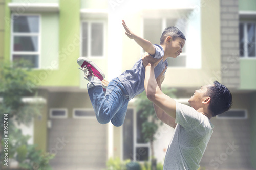 Fototapeta Naklejka Na Ścianę i Meble -  Young father lifting his son at outdoors