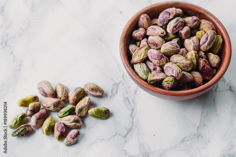 Pistachios in wooden bowl on marble background with copy space Pistachios in wooden bowl on marble background with copy space