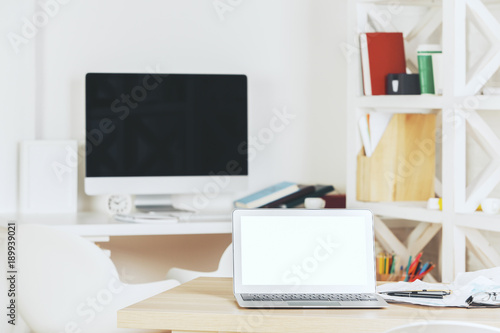 Designer workspace with blank white laptop