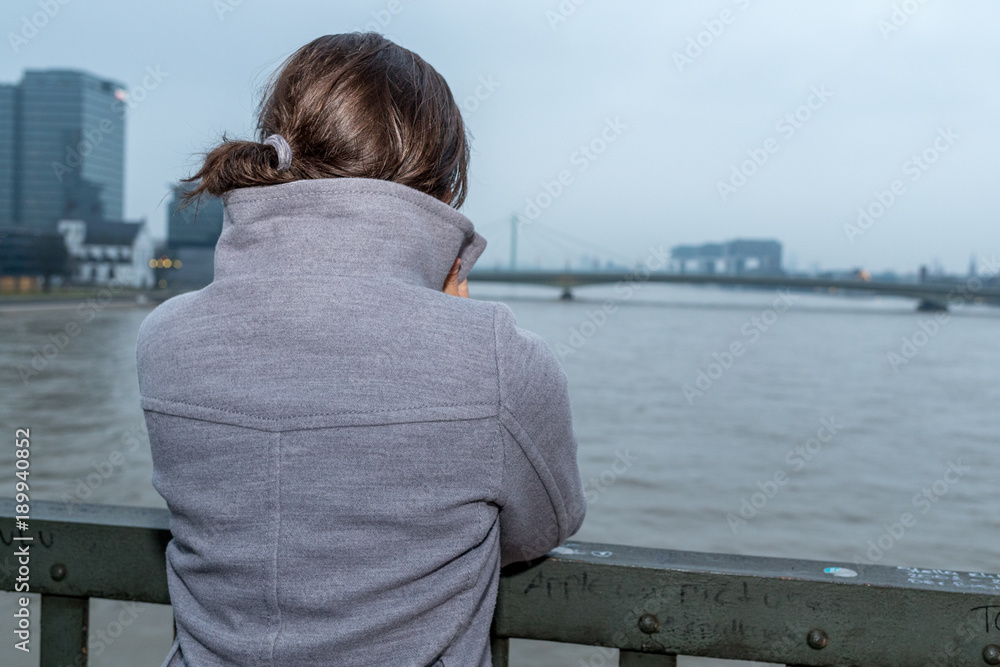Junge Frau schaut auf den Rhein bei Köln