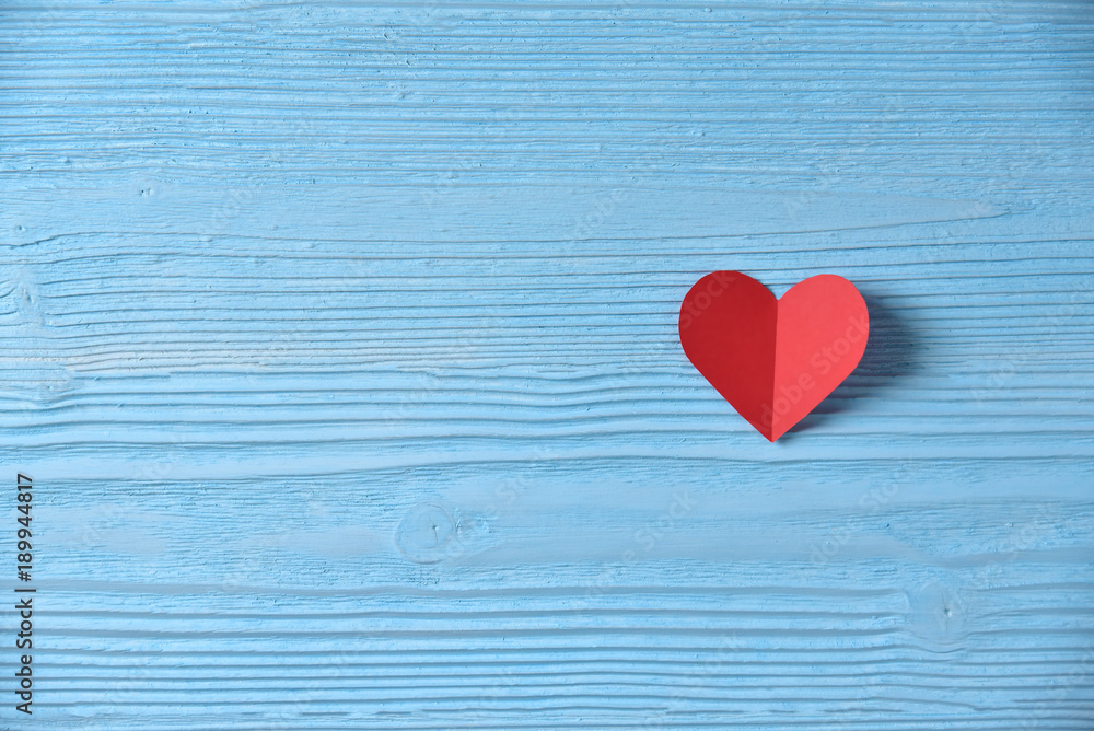 Red heart on blue wooden background.