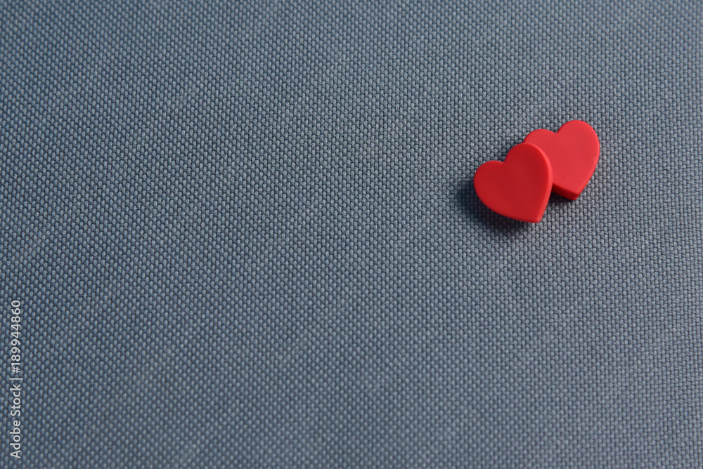 Fototapeta premium Two Red hearts on grey fabric texture background.