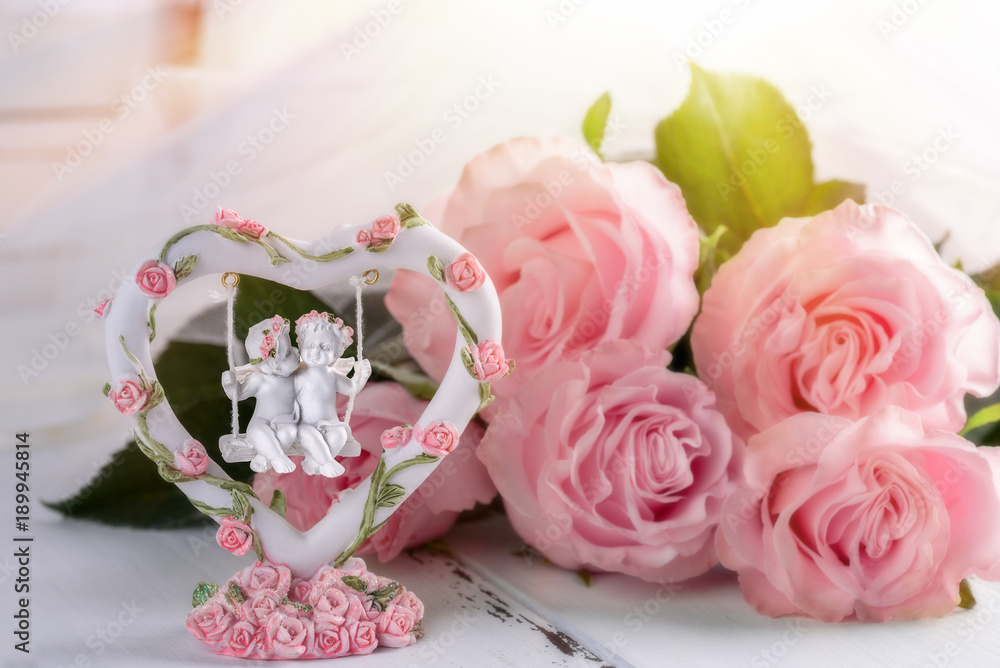 Postcard to Valentine's Day: loving angels on a swing and pink roses