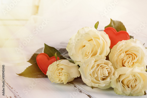 Roses and red hearts on a white wooden background