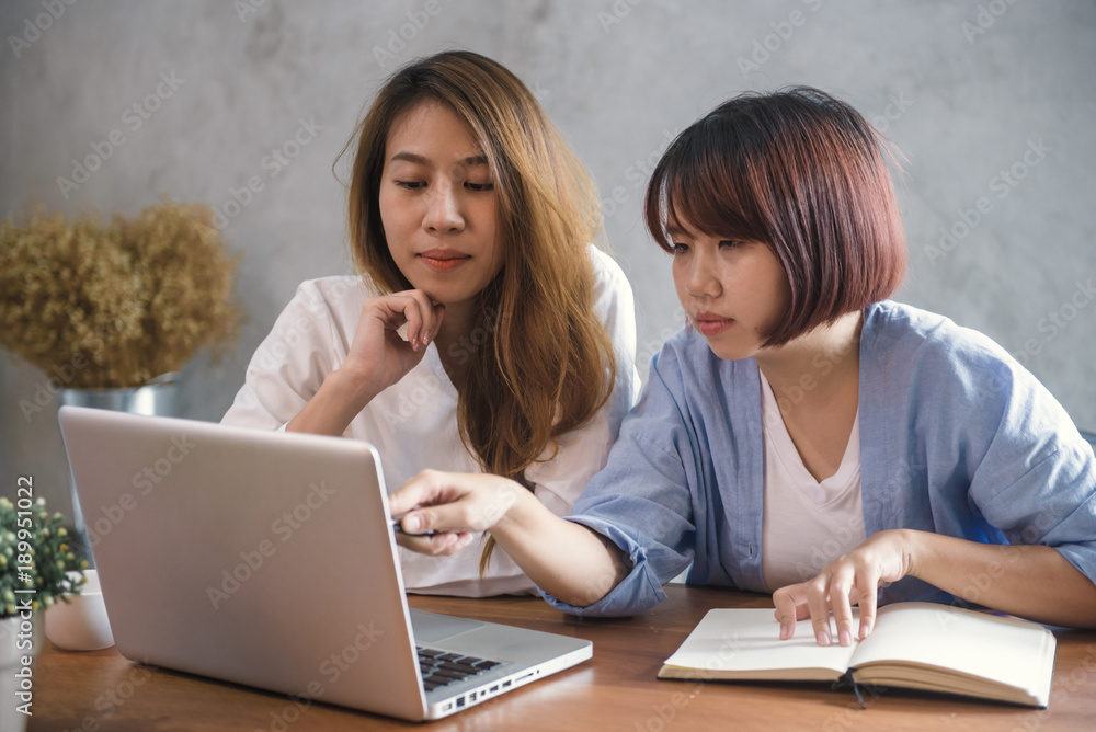 Two young business women sitting at table in cafe. Asian women using laptop and cup of coffee. Freelancer working in coffee shop. Working outside office lifestyle. One-on-one meeting. Two young business women sitting at table in cafe. Asian women using laptop and cup of coffee. Freelancer working in coffee shop. Working outside office lifestyle. One-on-one meeting.