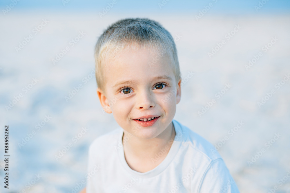 Adorable portrait of a happy boy, smiling at the camera in the sand near the sea, ocean. Positive human emotions, feelings, joy. Funny cute child taking vacations and enjoying summer. Adorable portrait of a happy boy, smiling at the camera in the sand near the sea, ocean. Positive human emotions, feelings, joy. Funny cute child taking vacations and enjoying summer.