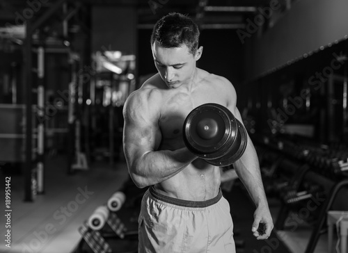 Muscular young bodybuilder training in gym, black and white effect