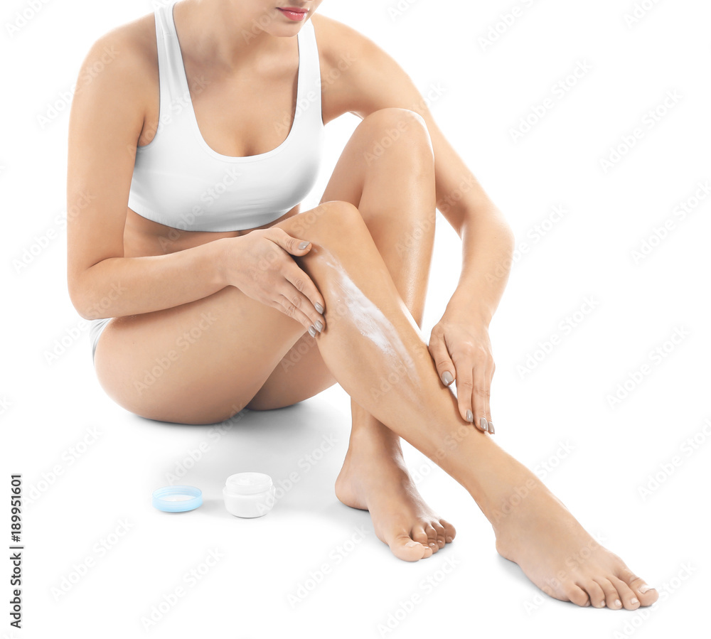 Woman applying body cream on her leg against white background