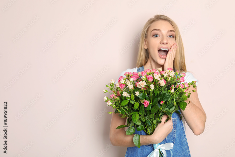 Beautiful young woman with bouquet of roses on color background