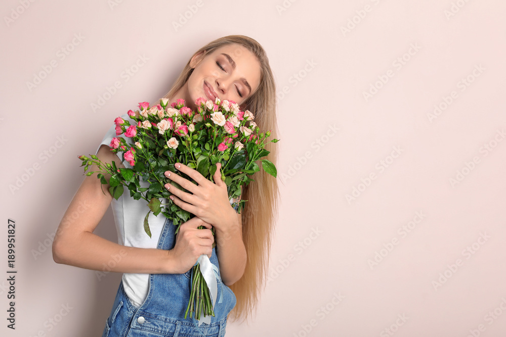 Beautiful young woman with bouquet of roses on color background