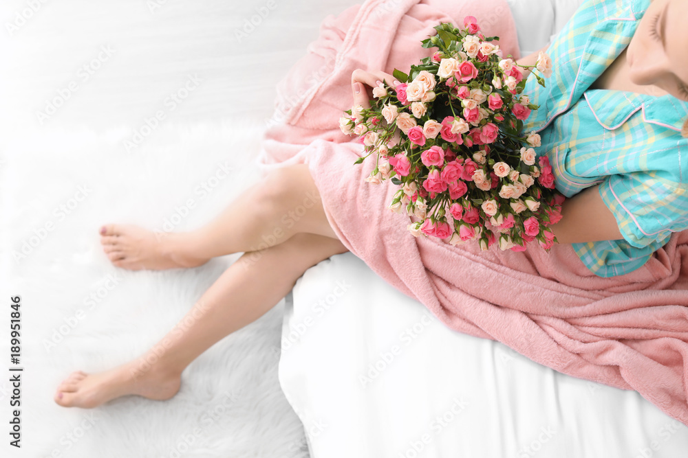 Young woman with bouquet of roses on bed at home Young woman with bouquet of roses on bed at home