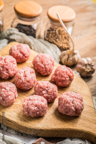 Raw meatballs on the wooden cutting board.