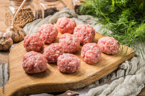 Obraz na plátně Raw meatballs on the wooden cutting board.