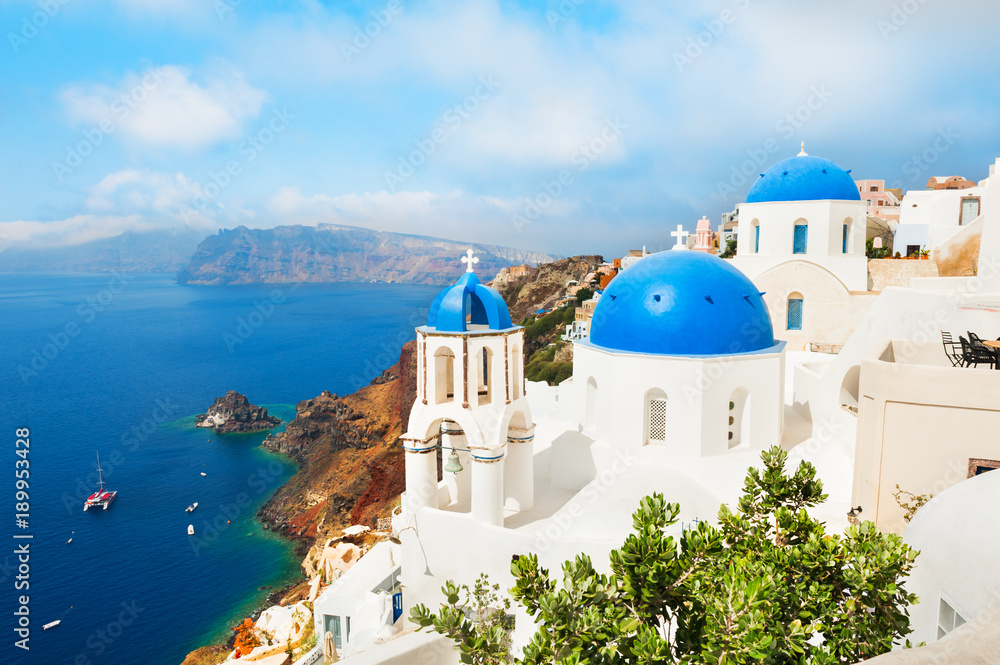 Fototapeta Santorini island, Greece. White church with blue domes against the blue sea