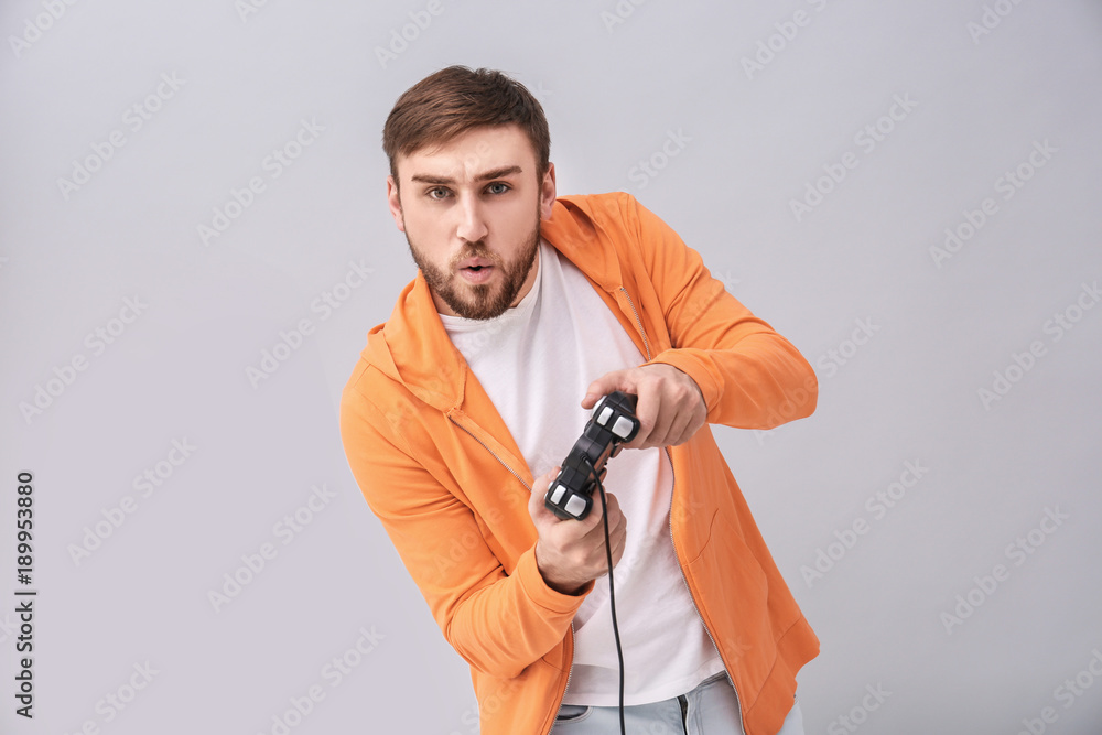 Emotional man with video game controller on grey background Emotional man with video game controller on grey background