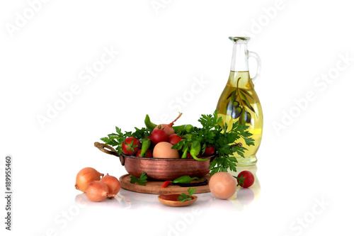 Menemen. Ingredients for cooking traditional Turkish fried eggs with tomatoes. In the frypan, olive oil, chicken eggs, ripe tomatoes, hot green peppers and spices. close-up still life.