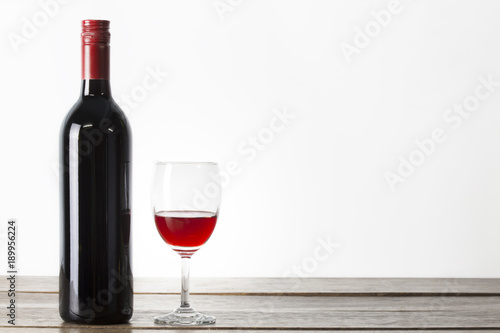 Wine bottle and wine glass on wooden table and white background isolated copyspace.