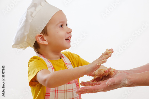 Details of children's hands kneading dough. Cheerful cook child boy in a cap prepares burritos photo