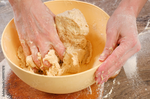 Unleavened dough for tortillas with flour and hand on kitchen table. Cooking burrito. photo