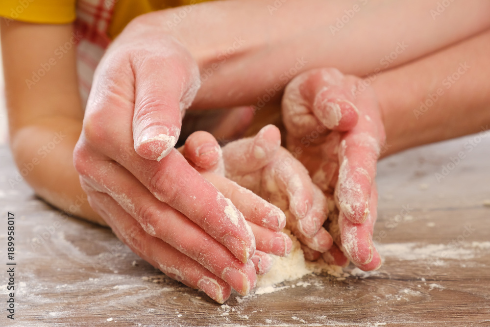 Close up of children's and mother's hands kneading dough. Child prepares burritos or burrito