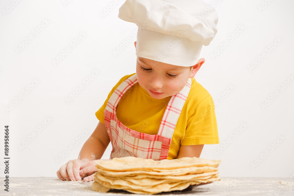 Child chef cook and Stack of homemade whole wheat flour tortilla on wooden table Child chef cook and Stack of homemade whole wheat flour tortilla on wooden table