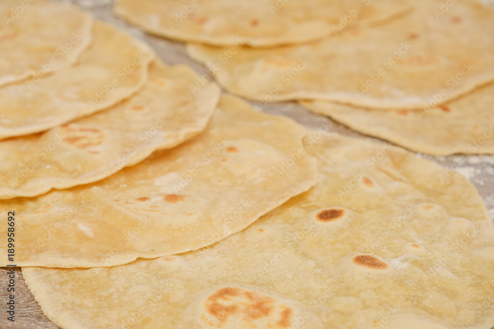 Stack of homemade whole wheat flour tortilla on wooden table Stack of homemade whole wheat flour tortilla on wooden table