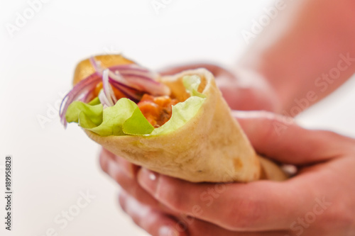 Mexican burrito in hand with chicken, pepper and beans photo