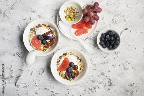 Seasonal healthy breakfast: yoghurt, chocolate granola, pink grapefruit, grapes, pistachios. Top view. Copy space. flat lay