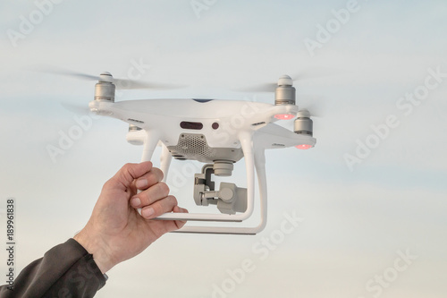The hand holds the dron at landing. Landing a droned hand with spinning propellers. Flying drone on the sky.