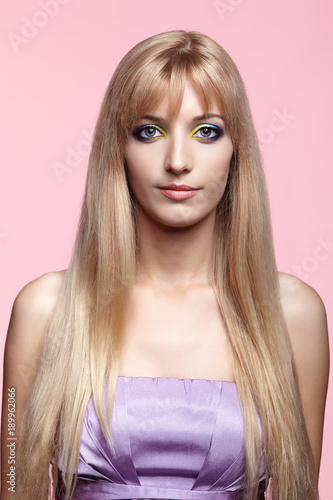 Young woman with long blond hair on pink background. © Serg Zastavkin