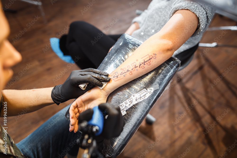 master tattooist makes a tattoo on girl hand