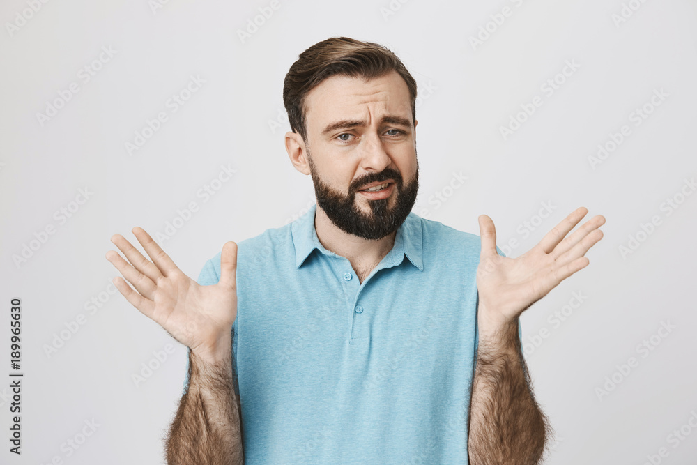 Portrait of a man with a beard raising his hands looking uncertain ...