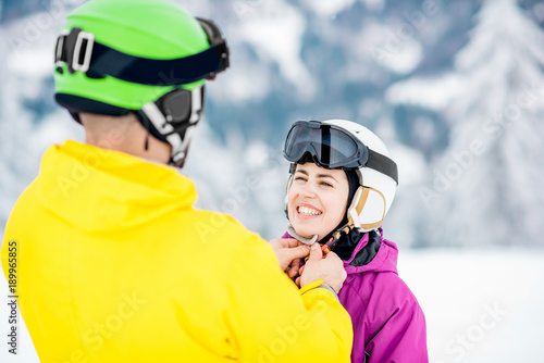 Young couple wearing sports helmet during the winter vacation on the snowy mountains