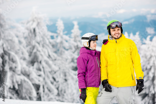 Young couple standing in winter sports clothes during the winter vacation on the snowy mountains